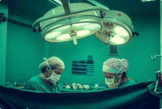 Two locum tenens surgeons performing a weight loss gastric bypass surgery under bright operating room lights.